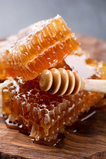 Honeycombs and wooden honey dipper. Closeup view
