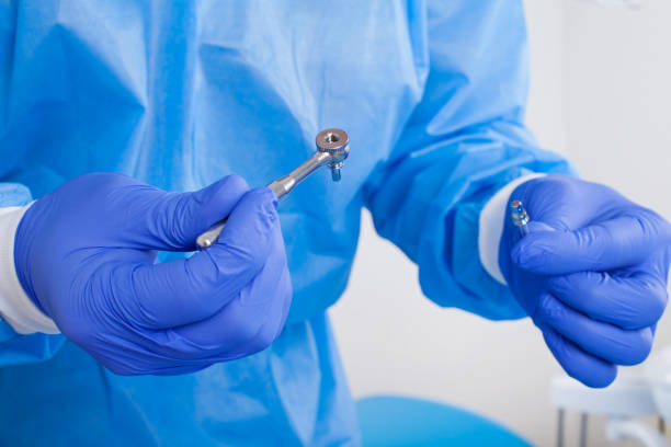 Dental surgery Close up picture of dental surgeon wearing blue gloves and coat, holding a dental drill dental drill stock pictures, royalty-free photos & images