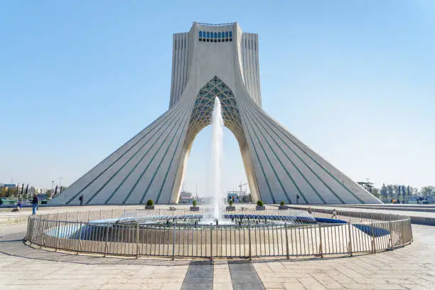 Scenic view of the Azadi Tower (Freedom Tower) on blue sky background and fountain on Azadi Square in Tehran, Iran. Tehran is a popular tourist destination of the Middle East.
