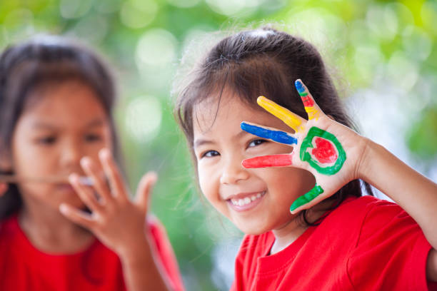 Cute asian little child girl with painted hands smiling with fun and happiness stock photo
