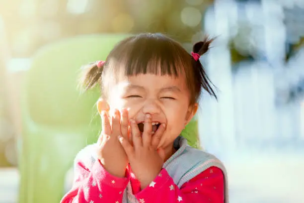Cute asian baby girl laughing and playing peekaboo or hide and seek with fun