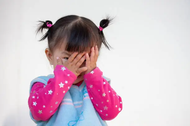 Cute asian baby girl closing her face and playing peekaboo or hide and seek with fun