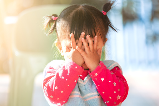 Cute asian baby girl closing her face and playing peekaboo or hide and seek with fun