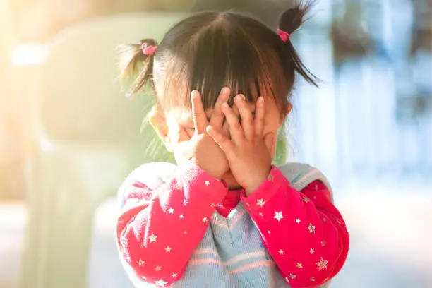 Photo of Cute asian baby girl closing her face and playing peekaboo or hide and seek