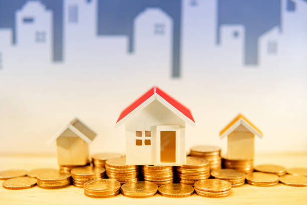 Real estate or property investment concept. Home mortgage loan rate. Gold coins stack and house models on the table with white city skyline background. Saving money for future retirement. concepto de inversiones inmobiliarias o inmobiliarias. tasa de préstamos hipotecarios domiciliarias. monedas de oro pila y modelos de la casa en la mesa con fondo de la ciudad blanca horizonte. ahorrando dinero para futuras jubilaciones.