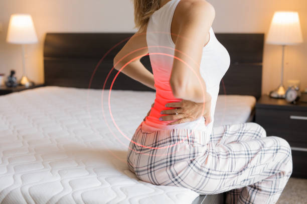 woman suffering from back pain because of uncomfortable mattress - back rear view pain backache imagens e fotografias de stock