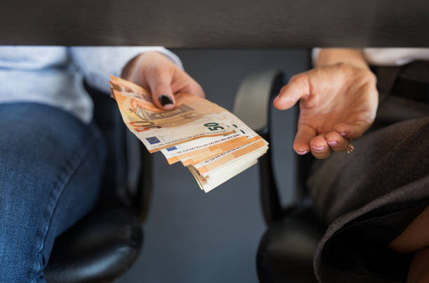 Two persons giving and taking a bribe money below table