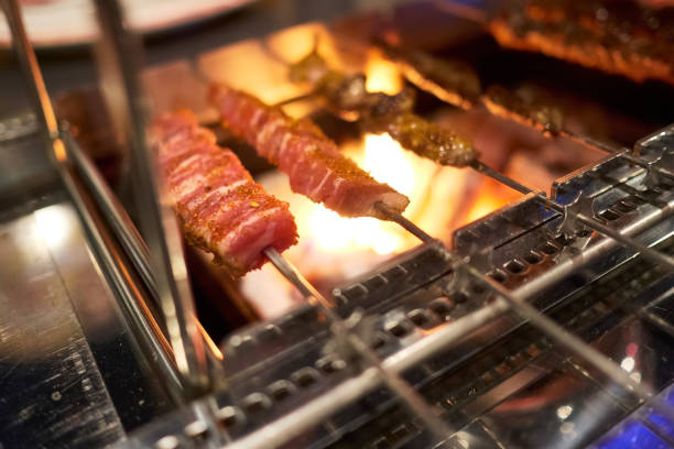 A few meat skewers is being grilled by charcoal flame stock photo