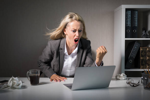 istock Woman angry at her laptop computer at work 1128831226