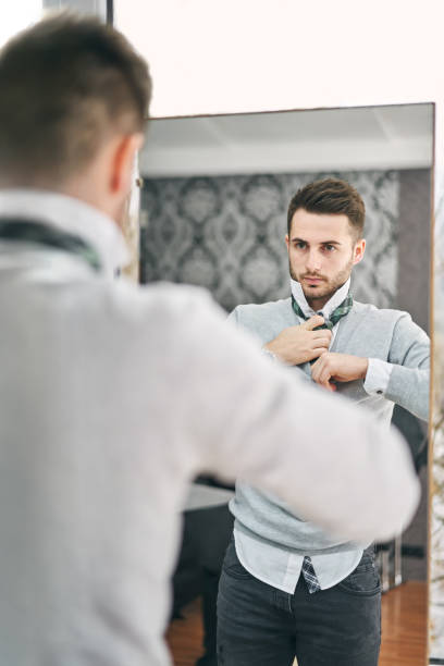 istock Handsome young man adjusting a tie in front of the mirror 1128832338