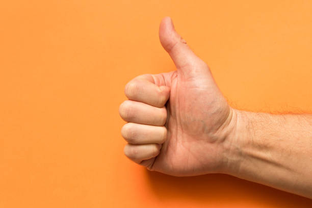 istock The hand of a man with his thumb up. On an orange background. Empty text space. 1128835897