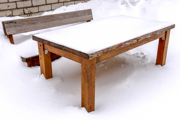 Wooden table and bench covered with snow