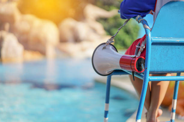 bagnino seduto sulla sedia con megafono a bordo piscina per proteggere vite - lifeguard swimming pool summer swimming foto e immagini stock