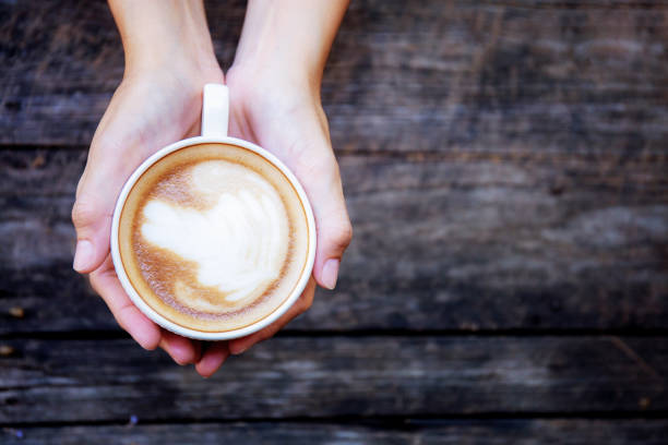istock Hands holding coffee cup on wood. 1128842398