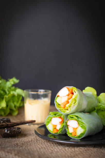 istock Salad rolls on black plate placed on a sack there is chopsticks, salad dressing and lettuce placed beside. 1128842942