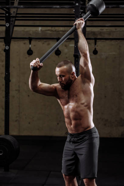 istock sporty man is doing exercises for arms with sledgehammer 1128845080