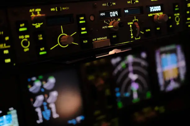 Airliners Cockpit with Pilots seen from behind in flight and in Duty. Pilots controlling and doing recent checks of instruments as their duty.