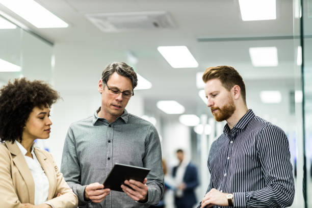 istock Business team cooperating while working on touchpad in a hallway. 1128847712