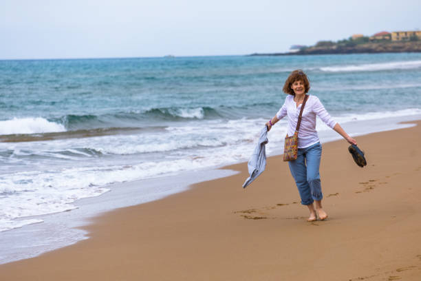 istock Woman walking along the beach 1128850974