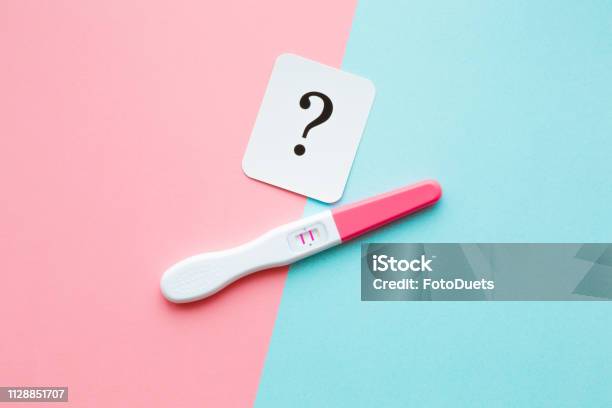 Pregnancy Test With Two Stripes And White Card Of Black Question Mark Pastel Blue And Pink Background Positive Result Guessing Unborn Baby Gender Closeup Stock Photo - Download Image Now