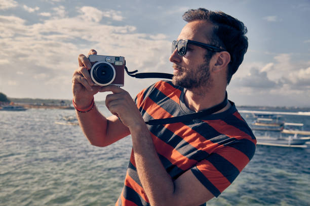 istock Man using vintage film camera on a ocean / sea vacation. 1128851716