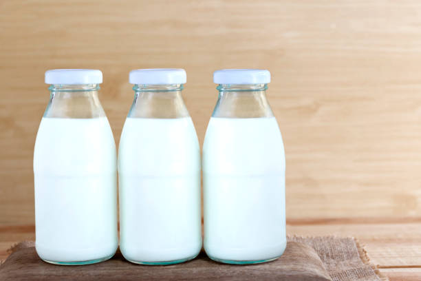 istock Three bottles of milk on a wooden table. Copy space for text or image. 1128853403