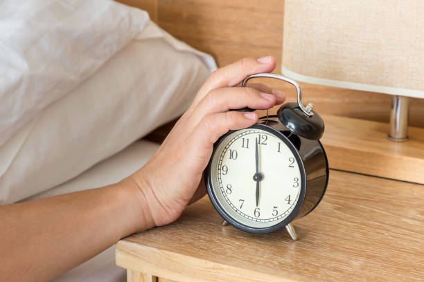 istock Man extend hand reaching to turn off alarm clock switch 1128856624