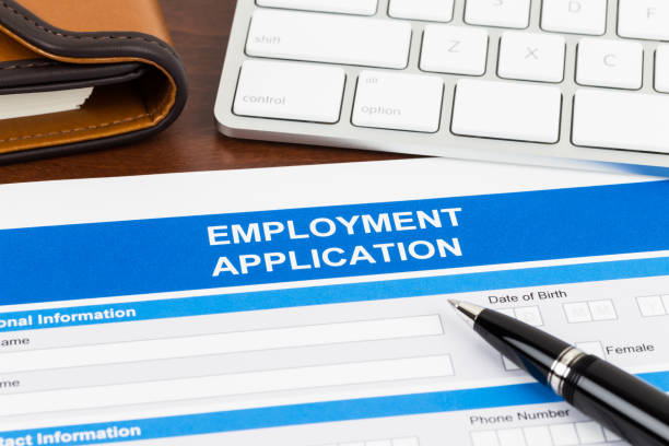 istock Employment application form with pen and keyboard; document is mock-up 1128856652