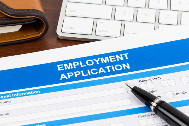 istock Employment application form with pen and keyboard; document is mock-up 1128856653