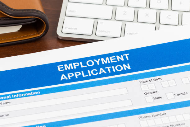 istock Employment application form with pen and keyboard; document is mock-up 1128856660