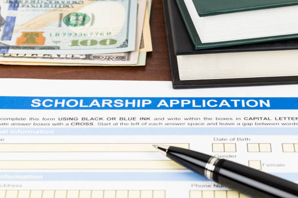 istock Scholarship application form with pen, dollar banknote and text book 1128856674