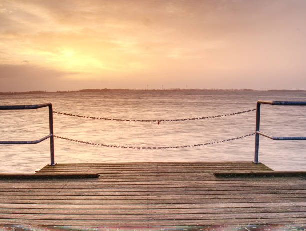 istock Long pier on Baltic coast in early morning calm. 1128856899