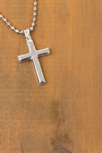istock Silver cross with necklace on wooden background 1128856975