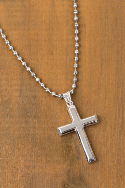 istock Silver cross with necklace on wooden background 1128856990