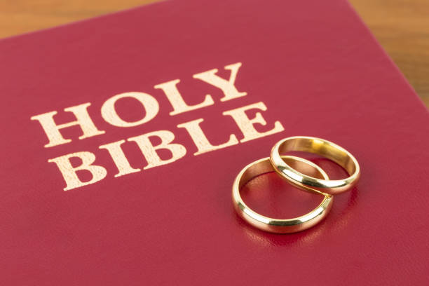 istock Gold wedding rings on red bible book cover 1128857021