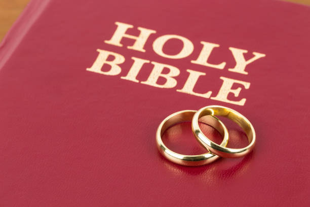 istock Gold wedding rings on red bible book cover 1128857027