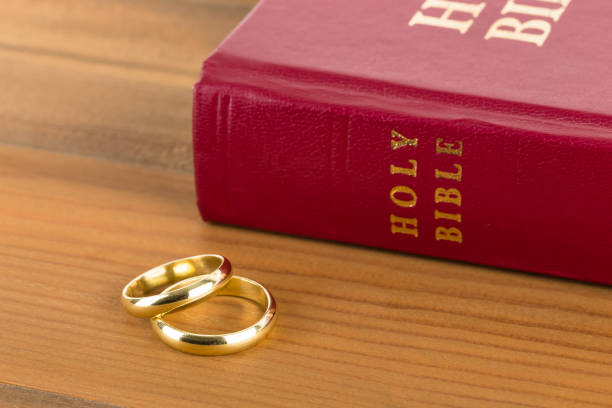 istock Gold wedding rings on wooden table and red bible book 1128857030
