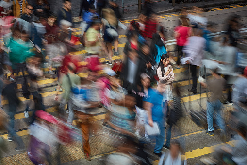 Long exposure image of Chinese businesswoman in a zebra crossing checking her mobile phone.