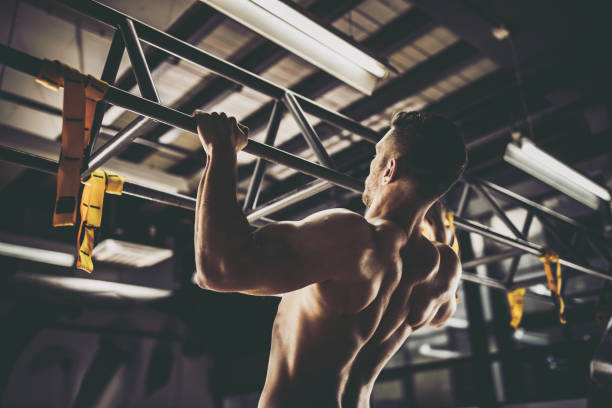 heckansicht des sportlicher mann klimmzüge in einem fitnessstudio trainieren. - masculinity stock-fotos und bilder