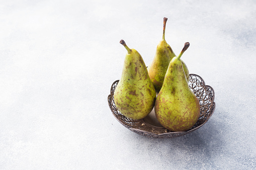 Fresh juicy Pears Conference in a basket on a grey background. Selective focus. Copy space.