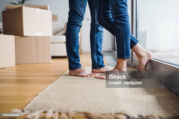 A Midsection Of Young Couple Moving In A New Home Standing By A Window Stock Photo - Download Image Now
