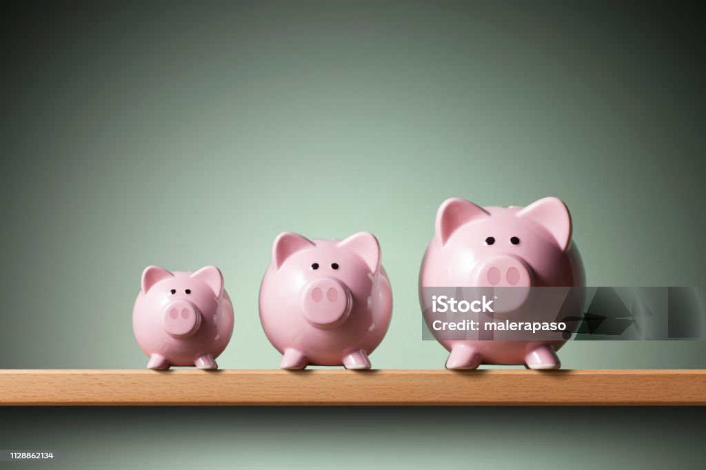 Three piggy banks on the shelf. 	Small, medium and large. Three piggy banks on the shelf. Small, medium and large. Growth Stock Photo