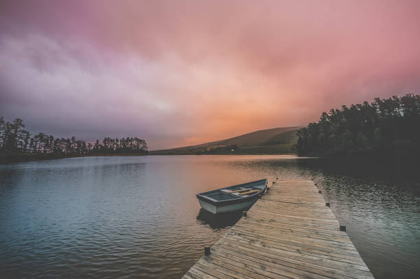 istock Moored rowboat and jetty serenity scene at dawn wide angle 1128863410