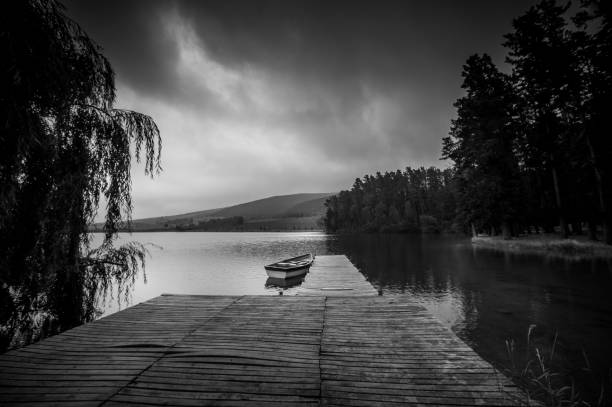 black and white moored rowboat and jetty serenity scene at dawn - loch rowboat lake landscape imagens e fotografias de stock