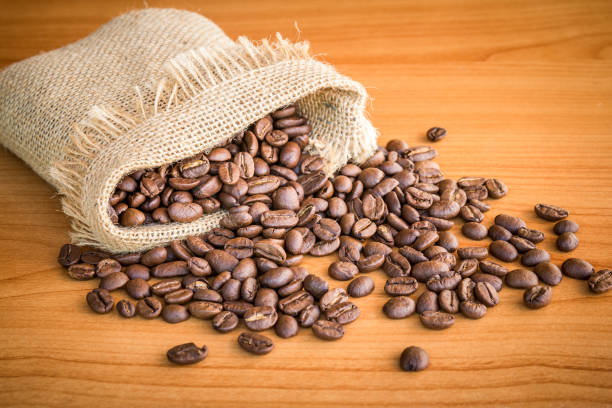 istock Sack of coffee beans on wooden background 1128865575