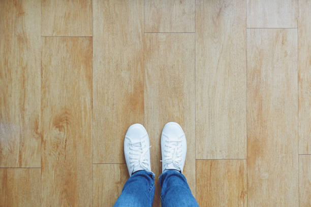 Selfie di piedi in sneakers di moda su sfondo pavimento in legno, vista dall'alto con spazio di copia - foto stock