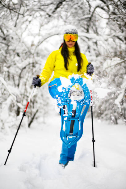 istock Female hiker threading through the deep snow in a frozen winter forest using her snowshoes 1128868281