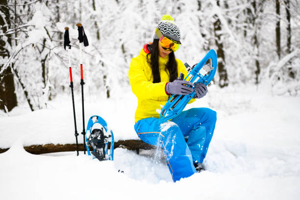istock Female hiker checking a binding system on her snowshoe while sitting down in a frozen forest 1128869497