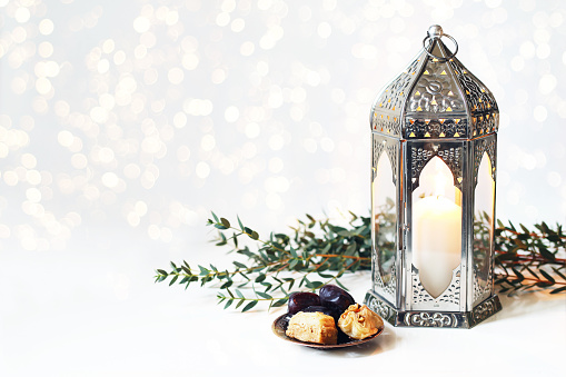 Ramadán Kareem tarjetas de felicitación, invitación. Placa de bronce con la fruta de las fechas, baklava pastelería, ardiente plata marroquí, Árabe la linterna en mesa blanca. Cena de Iftar. Luces brillantes. Eid ul Adha fondo photo