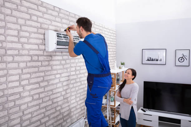 Male Technician Repairing Air Conditioner With Screwdriver Smiling Woman Looking At Male Technician Repairing Air Conditioner With Screwdriver In Home installing stock pictures, royalty-free photos & images